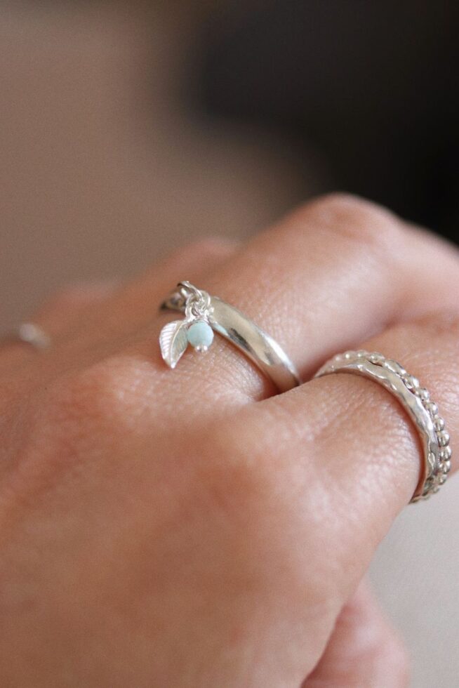 טבעת פס חלקה ודקה פתוחה מאחורה עם עלה קטן ואבן חן לרימר בצבע תכלת.jpg